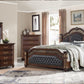 Luxurious bedroom set with dark wood furniture, including a bed, dressers, and mirror.