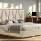 Beige upholstered bed in a bright bedroom with wooden desk and computer.