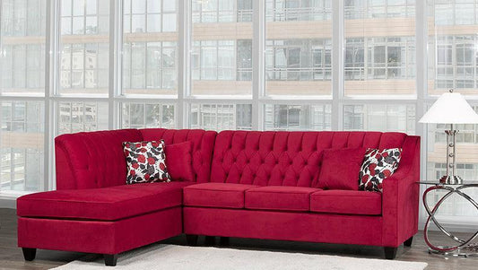 Red sectional sofa with patterned cushions in a room with large windows.